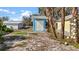 This backyard shows a shed, part of a yellow building, palm trees, and a yard with sandy areas at 7035 Duke St, Englewood, FL 34224