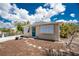 View of home with gravel driveway, shutters, and a bright blue door at 7035 York St, Englewood, FL 34224