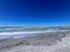 Beautiful beachfront view featuring gentle waves washing ashore under a bright blue sky at 8152 Little Gasparilla Is, Placida, FL 33946