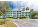 Beautiful multi-story building with a light teal exterior, lush landscaping, and ample parking at 8407 Placida Rd # 205, Placida, FL 33946