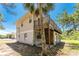 Charming two-story home showcasing a wooden balcony, lower-level arches, and lush foliage at 941 Allen Ave, Englewood, FL 34223