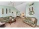 Comfortable living room with neutral carpet and light green walls, decorated with unique wall hangings and a ceiling fan at 941 Allen Ave, Englewood, FL 34223