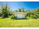 Exterior shot of a simple shed in a grassy yard surrounded by dense shrubs at 941 Allen Ave, Englewood, FL 34223