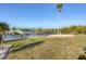 Spacious backyard with lush green grass, mature palm trees, a canal, and a covered boat lift at 15184 Aldama Cir, Port Charlotte, FL 33981