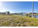 Spacious backyard with lush green grass, mature palm trees, a canal, and a covered boat lift at 15184 Aldama Cir, Port Charlotte, FL 33981