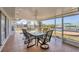 Covered and screened patio with tile floors, a ceiling fan, and dining set overlooking a canal at 15184 Aldama Cir, Port Charlotte, FL 33981
