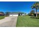 Charming single-story home featuring a well-manicured lawn, three-car garage, and tropical landscaping at 1078 Boundary Blvd, Rotonda West, FL 33947