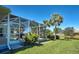 Backyard with a screened-in patio, pool, green grass, lake view, and palm trees at 1078 Boundary Blvd, Rotonda West, FL 33947