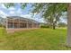 Spacious backyard featuring a screened-in patio and lush green lawn with mature trees at 1080 Boundary Blvd, Rotonda West, FL 33947
