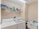 Functional laundry room with washer, dryer, sink, and storage shelves for supplies at 1080 Boundary Blvd, Rotonda West, FL 33947