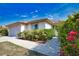 Attractive home exterior featuring a two-car garage, well-kept landscaping, and mature bougainvillea at 116 Albatross Rd, Rotonda West, FL 33947