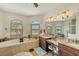 Well-lit main bathroom with dual sinks, vanity, soaking tub, and plantation shutters at 14527 Maysville Cir, Port Charlotte, FL 33981