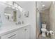 Updated bathroom with a white vanity, round mirror, and tiled shower with a shower curtain at 1551 Beach Rd # 412, Englewood, FL 34223