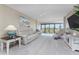 A bright living room with plush carpeting, comfortable seating, and sliding glass doors to a balcony at 1551 Beach Rd # 412, Englewood, FL 34223