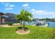 Serene backyard featuring lush lawn, mature palm trees, and a private boat dock on the water at 15588 Ruston Cir, Port Charlotte, FL 33981