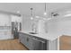 Modern kitchen features stainless steel appliances, gray cabinetry, a large island, and stylish pendant lighting at 1826 Narrington Ave, North Port, FL 34288