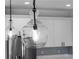 Modern pendant lighting with glass fixture hanging above kitchen island with white cabinets at 1826 Narrington Ave, North Port, FL 34288