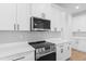 Clean white kitchen with stainless steel oven and microwave, light gray subway tile, and white quartz countertops at 1826 Narrington Ave, North Port, FL 34288