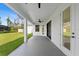 Covered patio with ceiling fan has view of backyard lawn with trees and shrubbery in the distance at 1826 Narrington Ave, North Port, FL 34288