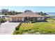 Exterior elevation of canal front home with 2-car garage and overgrown landscaping on a sunny day at 1905 Pennsylvania Ave, Englewood, FL 34224