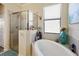 Bright bathroom featuring a glass shower enclosure and a luxurious soaking tub by a window at 20171 Tesoro Dr, Venice, FL 34293