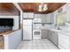 Cozy kitchen features gray cabinets, white appliances, and a connection to the living room at 2033 Georgia Ave, Englewood, FL 34224