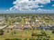 An aerial shot displays the homes setting within a neighborhood, screened in pool, and landscaping under a sunny sky at 212 Rotonda E Blvd, Rotonda West, FL 33947