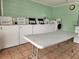 Community laundry room with many white washing machines, with a table in front, and tiled floor at 22375 Edgewater Dr # F219, Port Charlotte, FL 33980