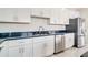Modern kitchen with stainless steel appliances, white cabinets, and a stylish black countertop at 234 Cougar Way, Rotonda West, FL 33947