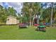 Backyard with multiple sheds, a trailer, a ride on lawnmower, and lush green grass at 2700 Sheboygan Ave, North Port, FL 34286
