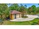 Detached garage with neutral siding, brown roof, and additional parking area surrounded by lush landscaping and mature trees at 2700 Sheboygan Ave, North Port, FL 34286