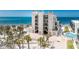 Stunning exterior view of the condo building with direct beach access, palm trees, and lush landscaping at 2792 N Beach Rd # 301, Englewood, FL 34223