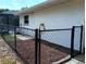 Home's fenced backyard featuring black chain link fence, bark landscaping, and view of screened pool at 3278 Cabaret St, Port Charlotte, FL 33948
