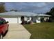 Well-maintained home with a metal roof, attached garage, and landscaped front yard with colorful flowering bushes at 3278 Cabaret St, Port Charlotte, FL 33948
