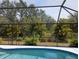 Inviting pool with clear blue water, seen through the screen enclosure with tropical landscaping at 3278 Cabaret St, Port Charlotte, FL 33948