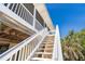 Exterior stairway ascending to a multi-story home featuring white railings and a clear blue sky at 342 S Gulf Blvd, Placida, FL 33946