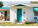 Single-story home showcasing a teal door, covered porch, and manicured lawn at 360 W Cowles St, Englewood, FL 34223