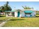 Charming single-story home featuring a covered porch, teal accents, and a well-manicured lawn at 360 W Cowles St, Englewood, FL 34223