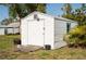 White outdoor shed with solid door, blue trim window, and ramp on a sunny day in the backyard at 360 W Cowles St, Englewood, FL 34223