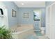 Cozy bathroom featuring a corner tub, tiled floors, and a large window at 4 Bunker Rd, Rotonda West, FL 33947