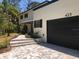 Home exterior featuring a dark garage, stone walkway, and lush landscaping at 425 Laurel W Rd, Nokomis, FL 34275