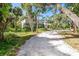 Well-maintained home exterior with lush landscaping and a gravel driveway nestled between mature trees at 425 Laurel W Rd, Nokomis, FL 34275