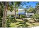 Beautifully landscaped two-story home with a metal roof and lush tropical surroundings, a gravel driveway leads to the garage at 425 Laurel W Rd, Nokomis, FL 34275