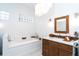 Bathroom with soaking tub, block glass window, wood cabinets, and a modern chandelier at 5 Saint John Blvd, Englewood, FL 34223