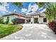Inviting single-story home with a tile roof, arched entryway, manicured lawn, and circular driveway at 5 Saint John Blvd, Englewood, FL 34223