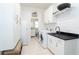 Bright laundry room with stainless steel appliances, white cabinetry, and a black countertop sink at 5 Saint John Blvd, Englewood, FL 34223