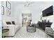 Bright living room with a modern white sofa, a large TV, and a view into an adjacent dining and kitchen area at 5 Saint John Blvd, Englewood, FL 34223