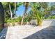 Paver patio area surrounded by lush tropical landscaping and mature trees at 5 Saint John Blvd, Englewood, FL 34223