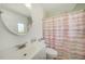 Clean bathroom featuring a white sink, round mirror, toilet, and a shower with a pink shower curtain at 5460 Norlander Dr, Port Charlotte, FL 33981