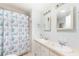 Well lit bathroom featuring double sinks and a shower/tub combo with coastal themed curtain at 6168 Partridge Ave, Englewood, FL 34224